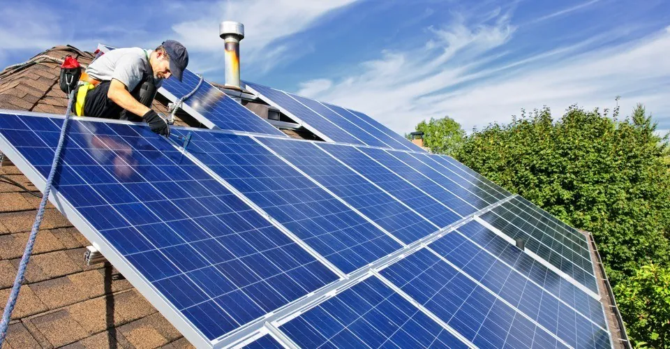 Instalatori montând panouri fotovoltaice pe un acoperiș